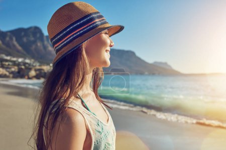 Téléchargez les photos : Portez un chapeau pour vous protéger du soleil. une belle jeune femme passant la journée à la plage - en image libre de droit