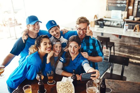 Foto de Hay que hacer recuerdos el día del partido. un grupo de amigos tomando una selfie mientras ven un partido de deportes en un bar - Imagen libre de derechos