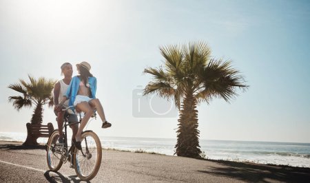Foto de Andar en bicicleta por la playa. una joven pareja montando una bicicleta juntos en el paseo marítimo - Imagen libre de derechos