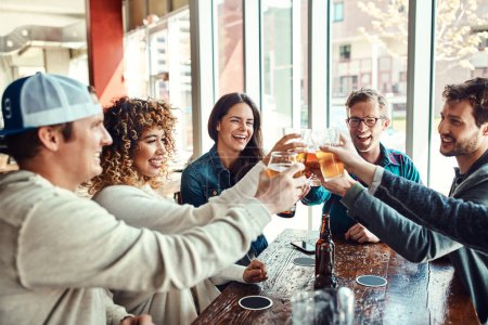 Foto de Las mejores cervezas son las que tomamos con los amigos. un grupo de amigos disfrutando en un bar - Imagen libre de derechos
