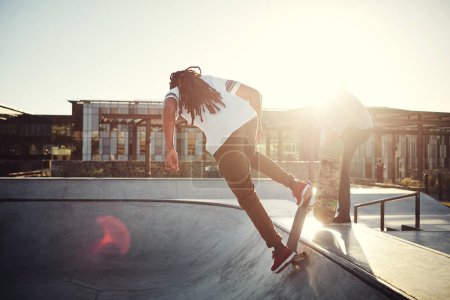 Foto de Técnica perfecta. Tiro de longitud completa de dos jóvenes patinando juntos en sus patinetas en un parque de skate - Imagen libre de derechos