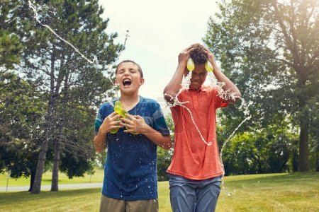 Photo for Cooling down the best way we know. adorable young boys playing with water balloons outdoors - Royalty Free Image