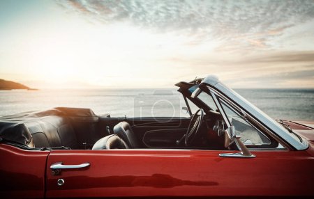 Téléchargez les photos : Passez cet été sur roues. une voiture vintage vide garée le long de la côte au coucher du soleil - en image libre de droit