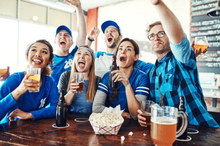 Téléchargez les photos : La folie du jour. un groupe d'amis qui applaudissent en regardant un match de sport dans un bar - en image libre de droit