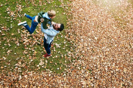 Téléchargez les photos : Ils s'amusent tout simplement ensemble. un père et son petit fils jouant à l'automne part à l'extérieur - en image libre de droit