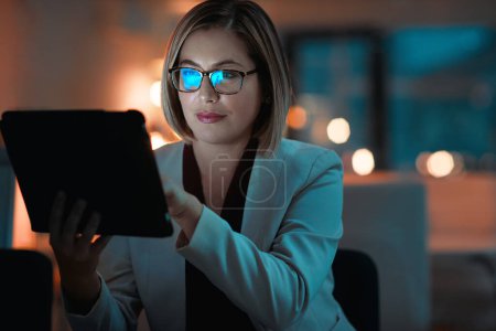 Foto de En línea no importa la hora. una mujer de negocios que usa una tableta digital durante una noche en el trabajo - Imagen libre de derechos