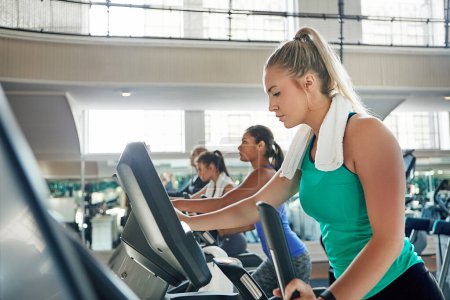 Foto de El compromiso quema calorías. una joven haciendo ejercicio con una máquina en un gimnasio - Imagen libre de derechos