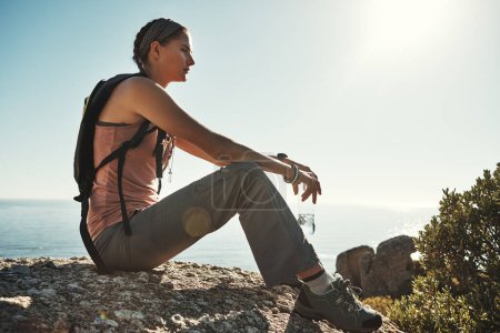 Foto de Parando para recuperar algo de energía. una joven tomando un descanso mientras que hacia fuera en una caminata a través de las montañas - Imagen libre de derechos
