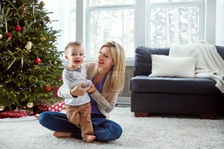 Foto de El mejor regalo que puede darle a su hijo es el tiempo. una joven madre disfrutando de la Navidad con su pequeño niño - Imagen libre de derechos