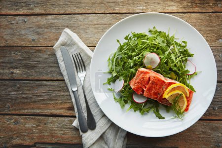 Foto de Es nutritivo y delicioso. un trozo de pescado cocido adornado con rodajas de limón y hojas frescas - Imagen libre de derechos