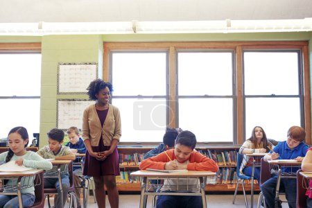 Téléchargez les photos : Évaluer leurs progrès. une enseignante dans une classe avec ses élèves - en image libre de droit