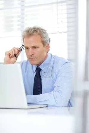 Photo for Making difficult business decisions. a mature businessman thinking while sitting in front of his laptop - Royalty Free Image