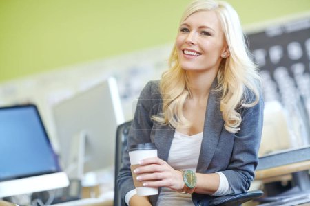 Téléchargez les photos : Portrait d'une femme d'affaires dans son bureau tenant une tasse de café. Femme souriante assise sur une chaise sur son lieu de travail. Heureux entrepreneur le matin seul dans une chambre - en image libre de droit