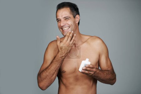 Photo for Hes a man that cares about skincare. Studio shot of a handsome mature man applying moisturizer to his skin - Royalty Free Image