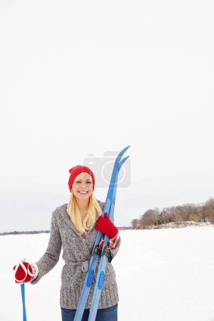 Foto de El día perfecto para una aventura de esquí. Tres cuartos de largo disparo de una hermosa mujer joven sosteniendo equipo de esquí - Imagen libre de derechos