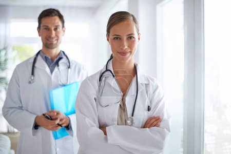 Téléchargez les photos : Bonne équipe de santé. Portrait de deux jeunes médecins debout dans un couloir d'hôpital - en image libre de droit