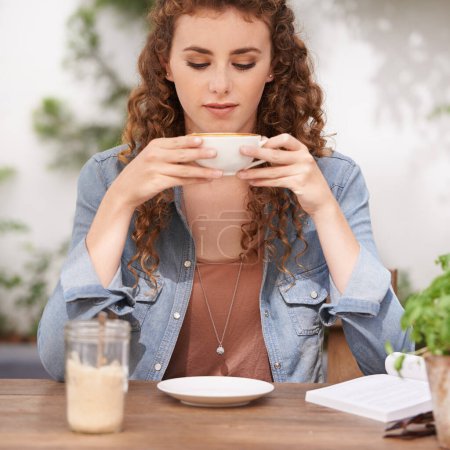 Foto de Relajarse con una taza de café fresco. una joven bebiendo café en un café - Imagen libre de derechos