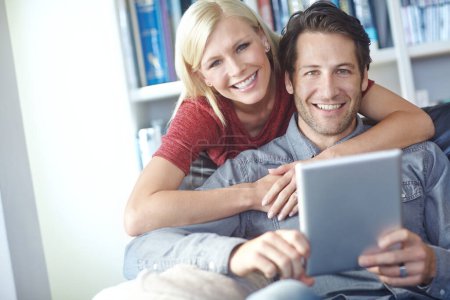 Téléchargez les photos : Planifier des vacances est si facile en ligne. Portrait d'un jeune couple utilisant une tablette numérique - en image libre de droit