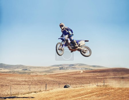 Photo for Going over a jump with style. a motocross rider in midair after hitting a jump - Royalty Free Image