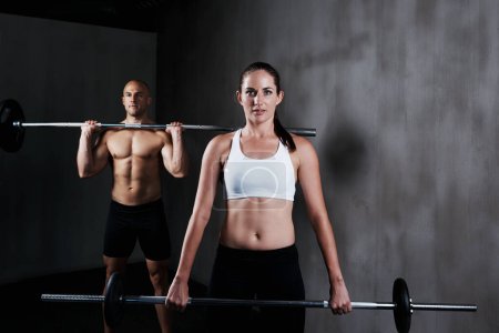 Foto de Entrenamiento para convertirse en combate en forma. un hombre y una mujer haciendo ejercicio con campanas - Imagen libre de derechos