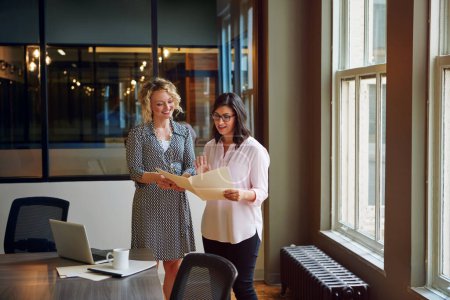Foto de Todo lo que queda es una firma. dos mujeres de negocios hablando juntas sobre el papeleo en una oficina - Imagen libre de derechos