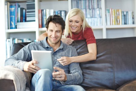 Photo for Making plans for dinner. a young man using a digital tablet while his girlfriend watches from behind - Royalty Free Image