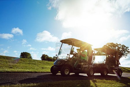 Foto de Gran día en los greens con buenos amigos. un grupo de amigos montando en un carrito de golf en un campo de golf - Imagen libre de derechos