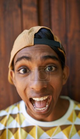 Téléchargez les photos : Ne soyez jamais trop sérieux. Portrait d'un adolescent faisant un visage debout contre un mur en bois - en image libre de droit
