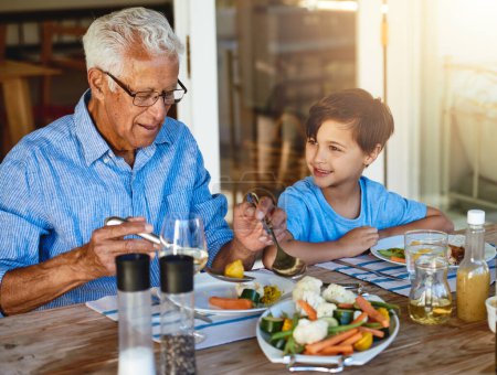 Foto de Cómete tus verduras, abuelo. una familia feliz disfrutando del almuerzo juntos alrededor de una mesa afuera - Imagen libre de derechos