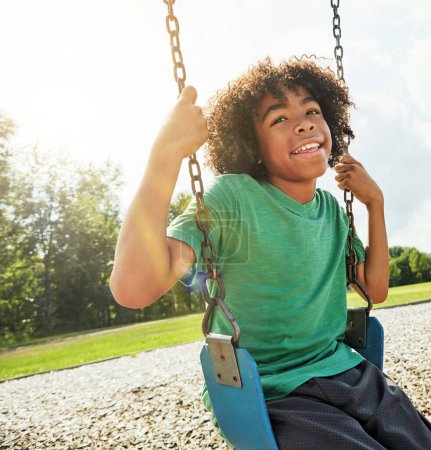 Téléchargez les photos : Le temps de jeu permet aux enfants d'apprendre et de développer des compétences essentielles. un jeune garçon jouant sur une balançoire au parc - en image libre de droit