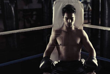 Photo for Hes found his place in the boxing ring. Portrait of a young male boxer sitting in a corner of a boxing ring - Royalty Free Image
