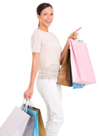 Photo for Have I got something for you. An attractive young woman carrying shopping bags and pointing to the side - Royalty Free Image