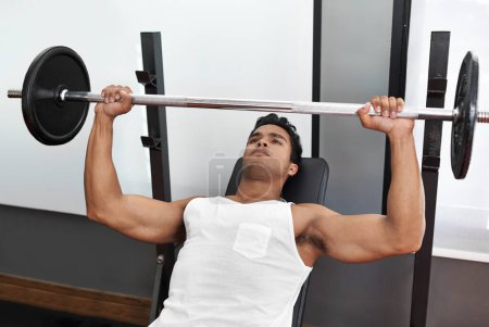 Photo for Feeling pumped. A young ethnic man lifting a heavy barbell in the gym - Royalty Free Image