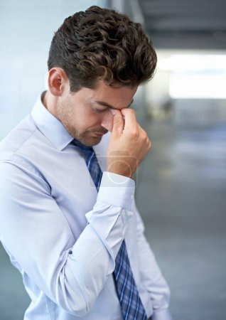 Burnout droht. Ein junger Geschäftsmann schaut gestresst ins Büro