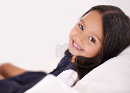 Téléchargez les photos : Le plus heureux à la maison. Portrait recadré d'une petite fille assise sur le canapé à la maison - en image libre de droit