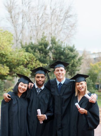 Photo for Theyve forged lifelong bonds. A group of college graduates standing in cap and gown and holding their diplomas - Royalty Free Image