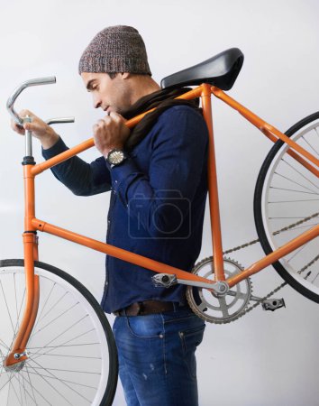 Téléchargez les photos : Se mettre au travail avec son fidèle vélo. un jeune homme branché portant son vélo à l'intérieur - en image libre de droit