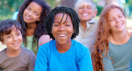 Téléchargez les photos : Camp d'été amusant. Un groupe d'enfants heureux souriant à la caméra assis à l'extérieur - en image libre de droit