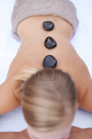 Foto de Tratamiento sereno de piedras. Una joven recibiendo un masaje de piedra caliente en un spa - Imagen libre de derechos