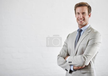 Téléchargez les photos : Confiant dans ses capacités d'affaires. Portrait d'un jeune homme d'affaires confiant debout contre un mur blanc - en image libre de droit