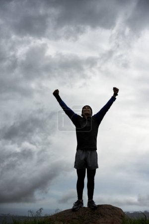 Téléchargez les photos : Triomphe au sommet. Un jeune homme célébrant au sommet d'une montagne après avoir atteint le sommet - en image libre de droit