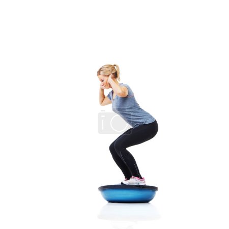 Foto de Su rutina de acondicionamiento físico es simple pero dura. Una hermosa joven haciendo ejercicio en una bola de bosu al revés - Imagen libre de derechos