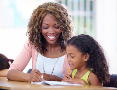 Photo for Shes passionate about teaching. A young teacher helping a pupil out with her schoolwork - Royalty Free Image