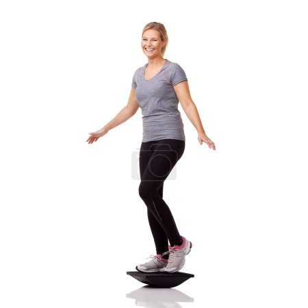 Photo for I can feel my muscles working. A pretty young woman exercising on a balance board while isolated on a white background - Royalty Free Image
