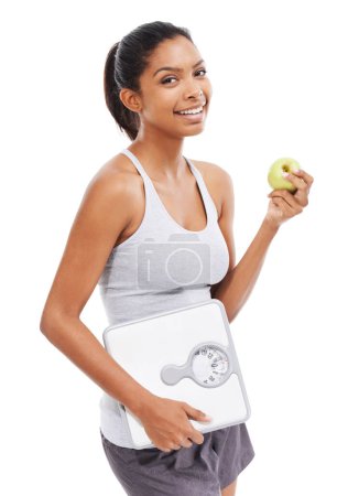 Téléchargez les photos : Suivre son régime alimentaire - et se sentir bien. Une magnifique jeune femme en tenue de sport tenant une pomme et une balance - en image libre de droit