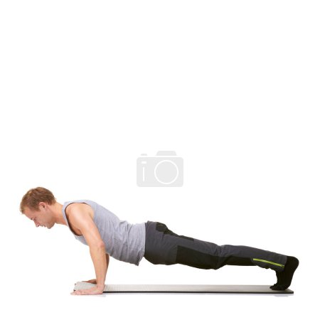 Foto de Fuerza y determinación - Fitness. Un joven en forma haciendo flexiones en su colchoneta mientras está aislado en blanco - Imagen libre de derechos