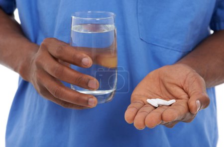 Foto de Tomando su dosis diaria. Vista recortada de un hombre sosteniendo unas tabletas blancas y un vaso de agua - Imagen libre de derechos