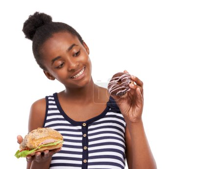 Foto de Te ves sabroso, Sr. Donut. Captura de estudio de una joven afroamericana tratando de elegir entre comer un donut o un sándwich - Imagen libre de derechos