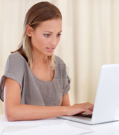 Foto de Ponerse al día con algunos correos electrónicos. Una joven sentada dentro y trabajando en su portátil - Imagen libre de derechos
