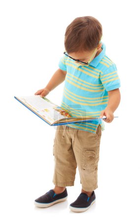 Photo for He loves his books. Full length studio shot of a young boy wearing glasses and reading a book - Royalty Free Image